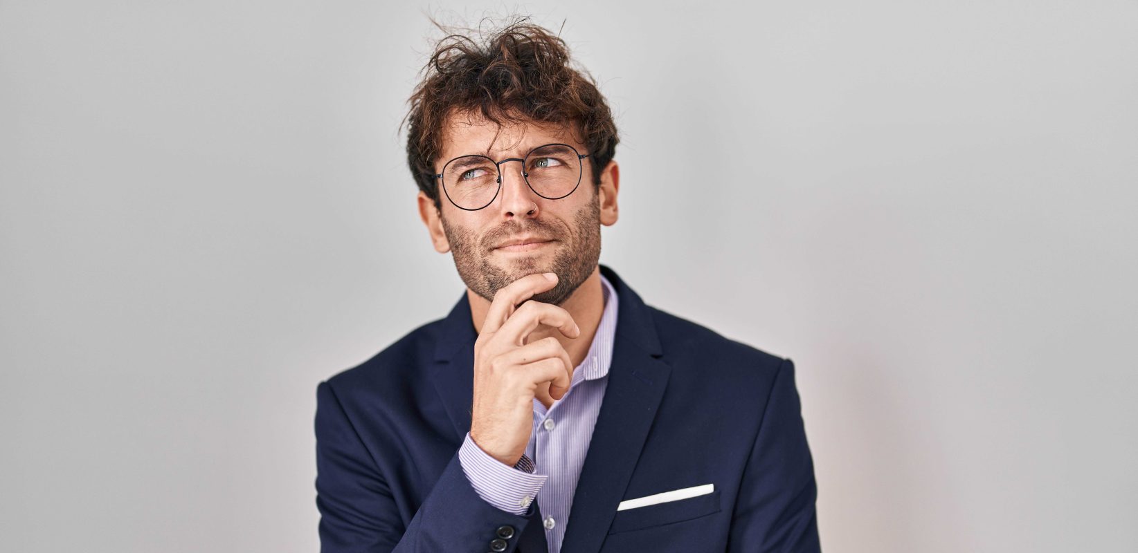 Hispanic business man wearing glasses with hand chin thinking about question pensive expression smiling with thoughtful face doubt concept copy