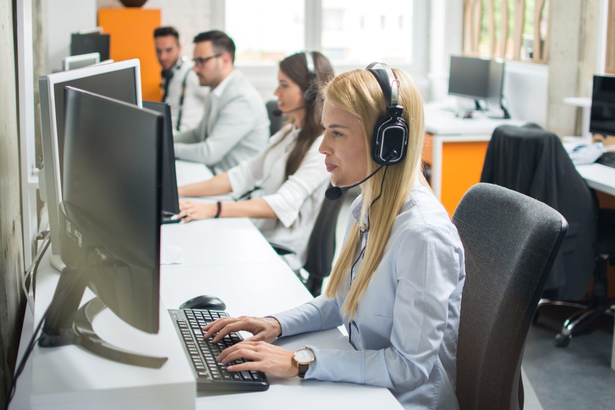Portrait beautiful young woman telephone operator with headset working desktop computer row customer service call support helpline center copy