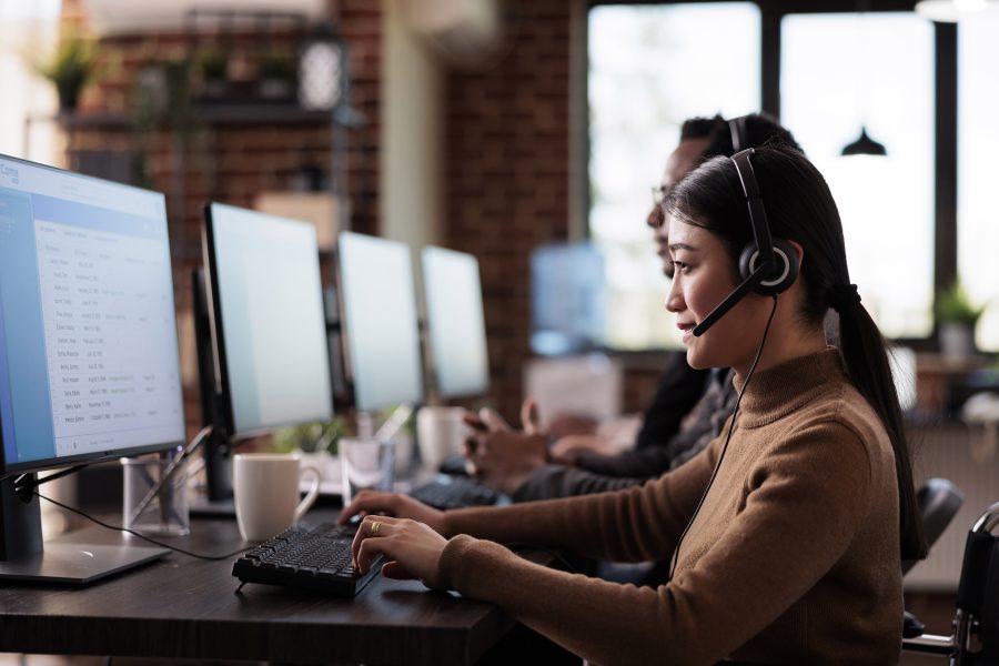 Paralyzed asian employee working call center reception disability friendly office female operator wheelchair user with impairment giving assistance customer service helpline 1