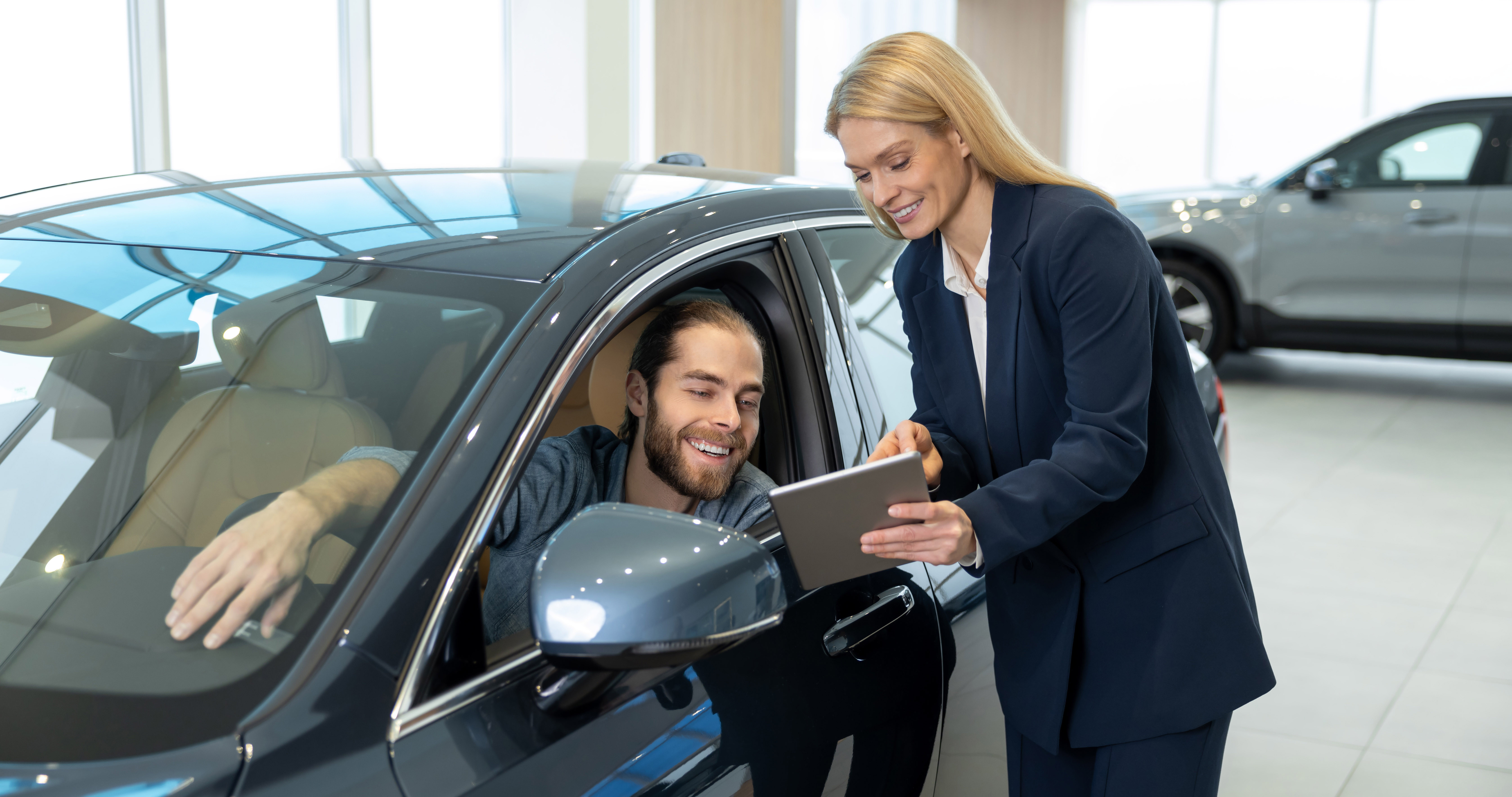 Blonde sale assistant showing something tablet customer dealership copy
