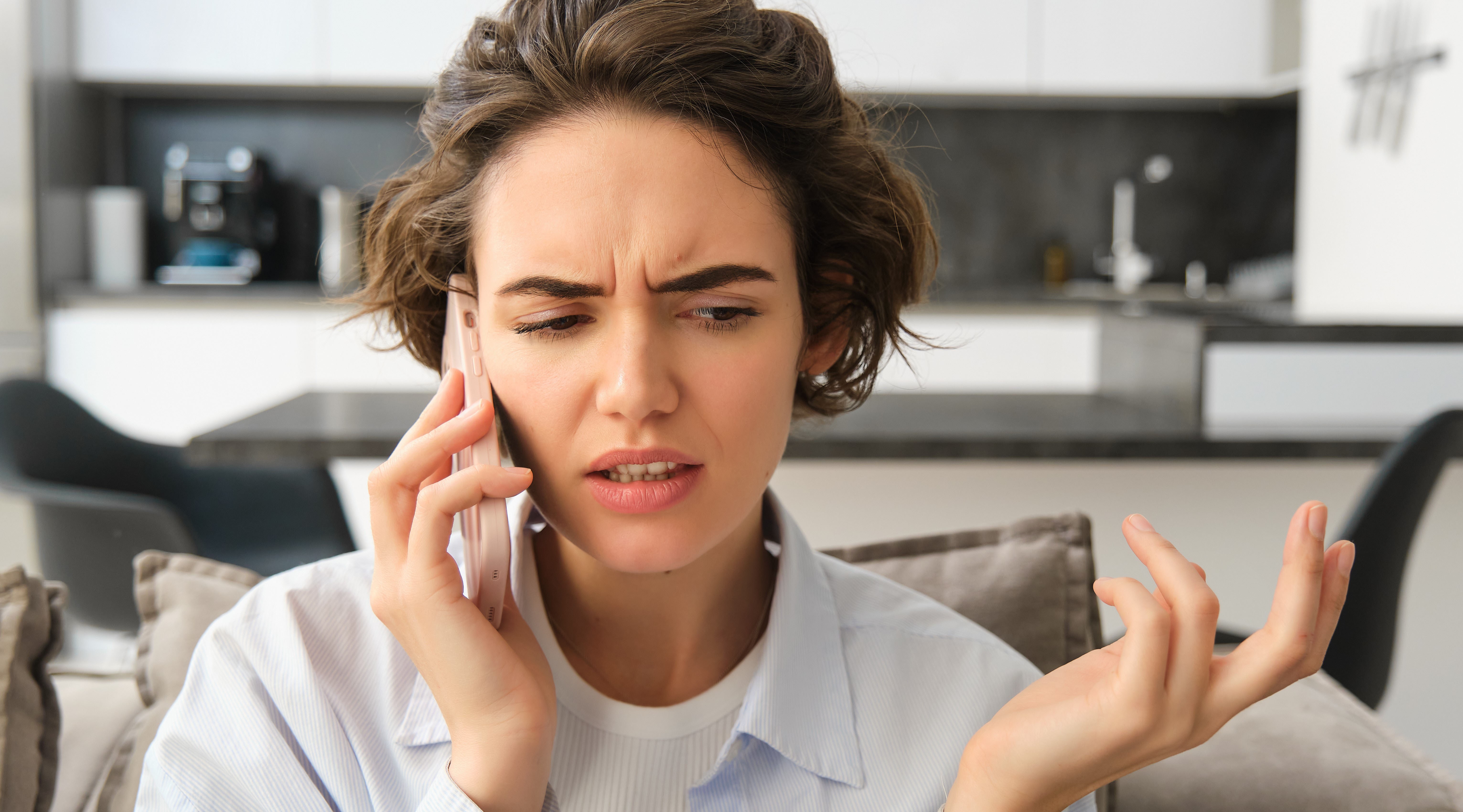 Close up portrait confused young woman answers phone call shrugs looks puzzled while listens