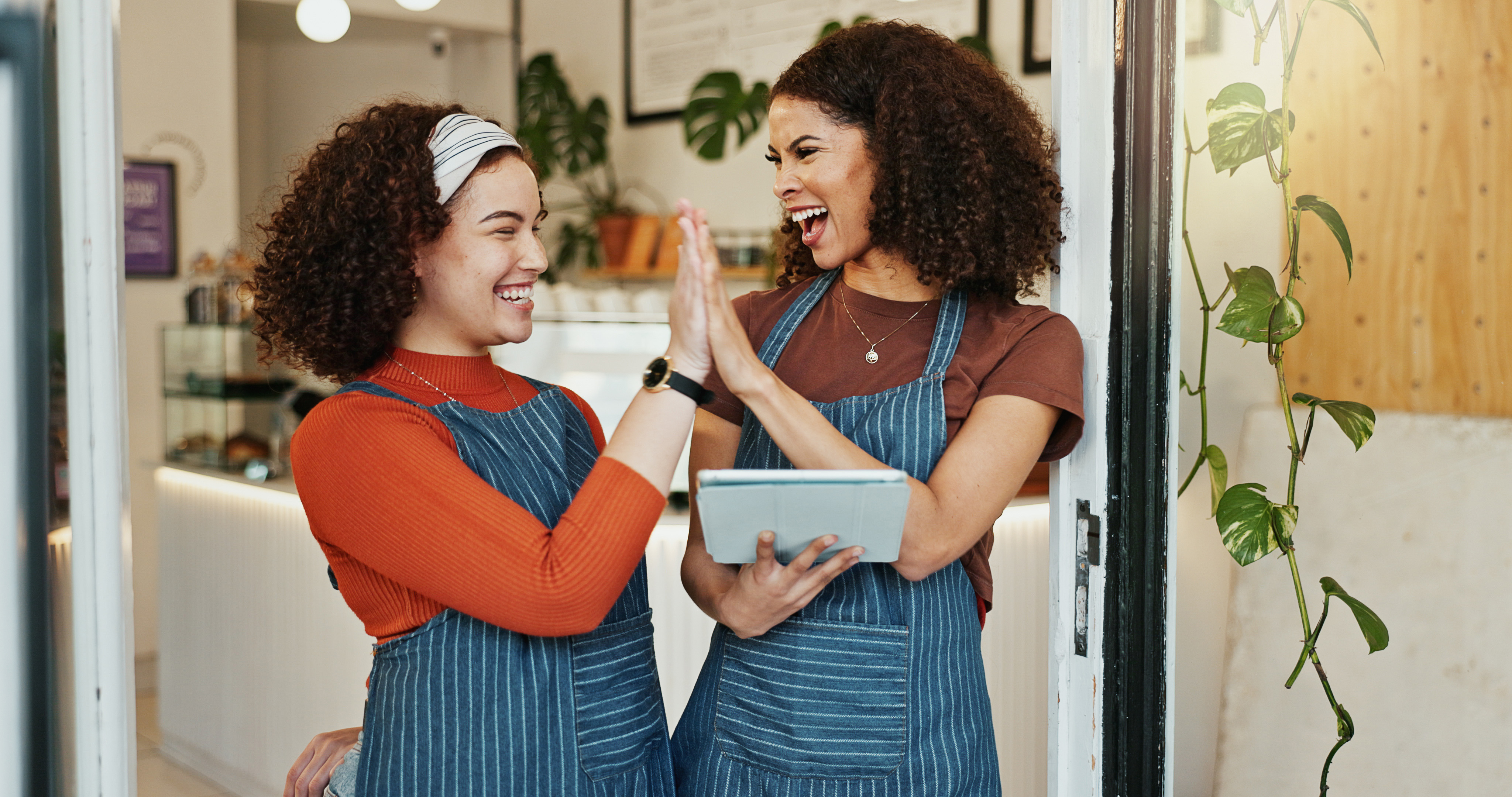Happy woman waitress high five with tablet teamwork success sale together cafe female person employees touching hands with smile technology online startup coffee shop copy